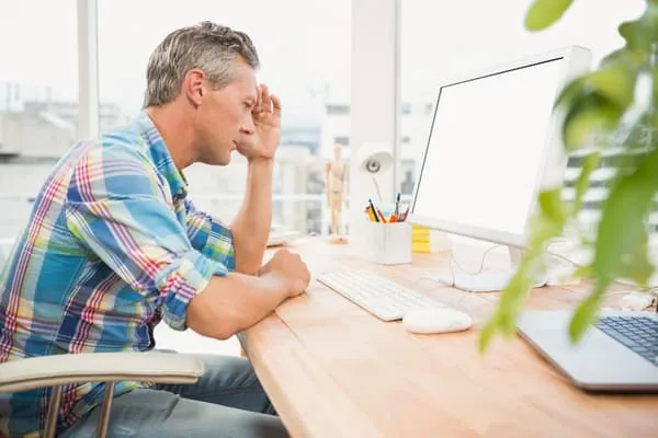 Man frustrated with the negative reviews, sitting in front of a computer. 
