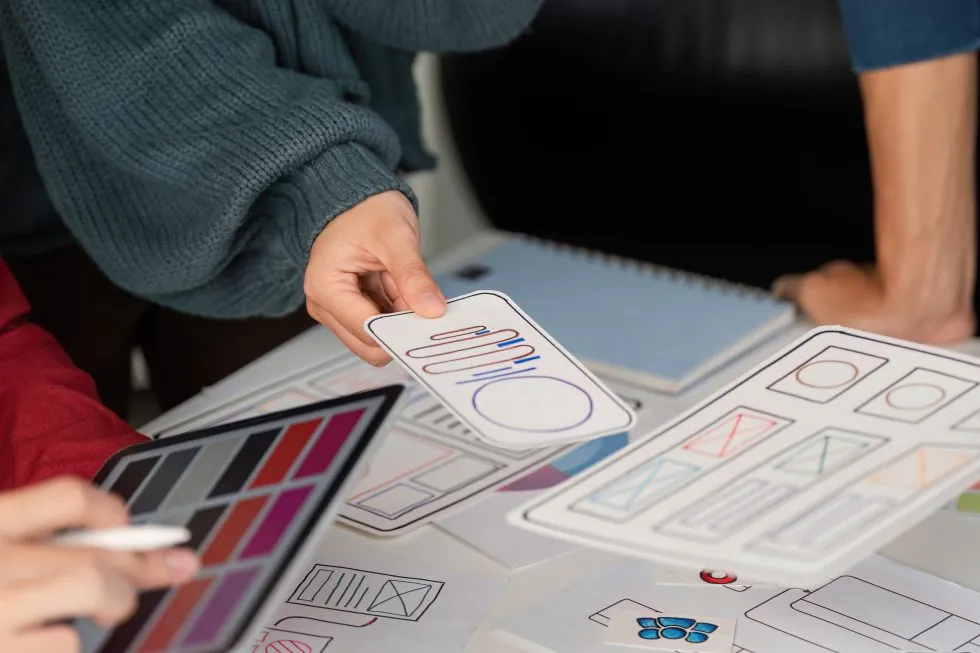 User experience design and presentation designers showcasing mobile user interface layouts while discussing project ideas