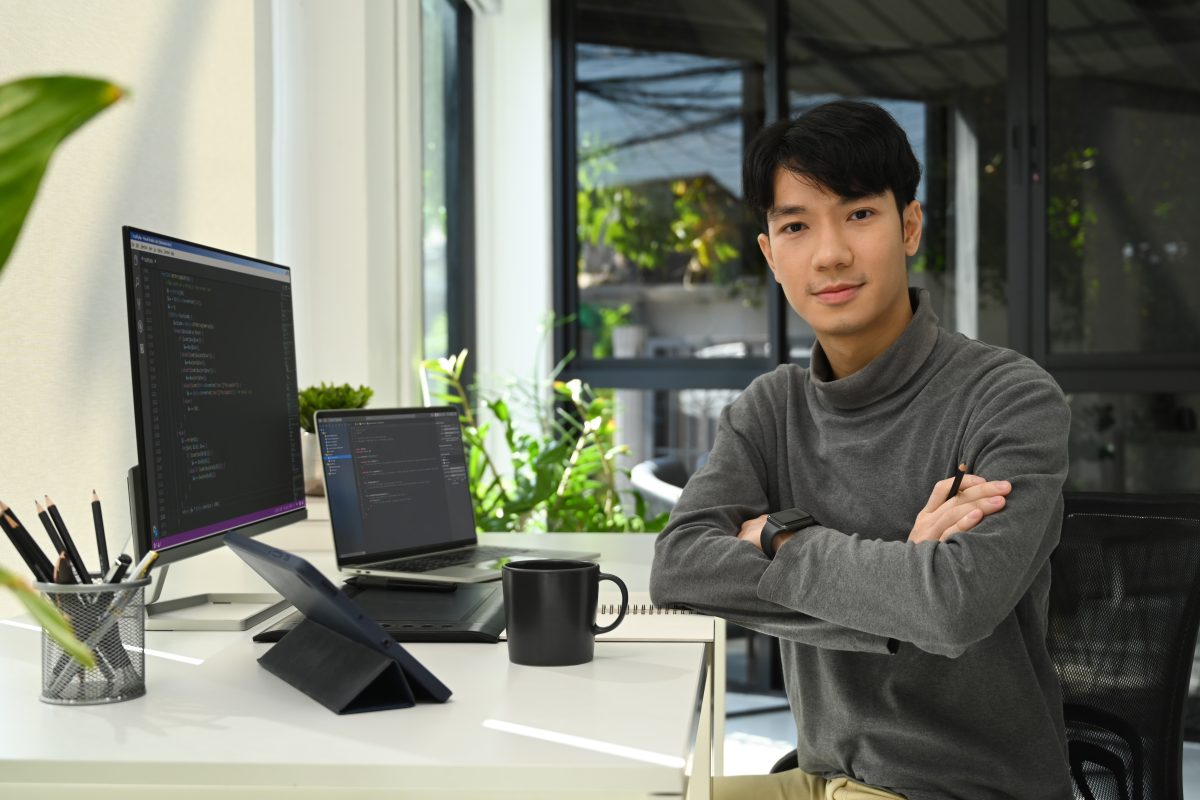 Why Small Businesses Need Professional WordPress Maintenance 2 49377844 young male website developer sitting front of computers with coded data on screen and smiling to camera 1