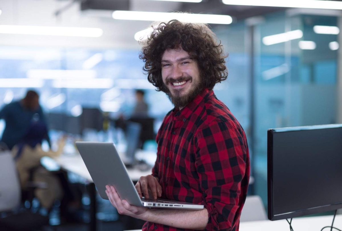 81681562 smiling male software developer using laptop scaled 1